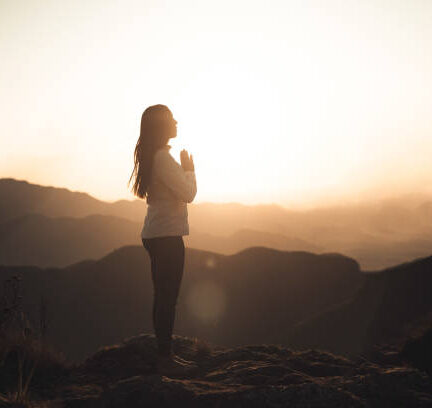Woman meditating at sunset in the mountains